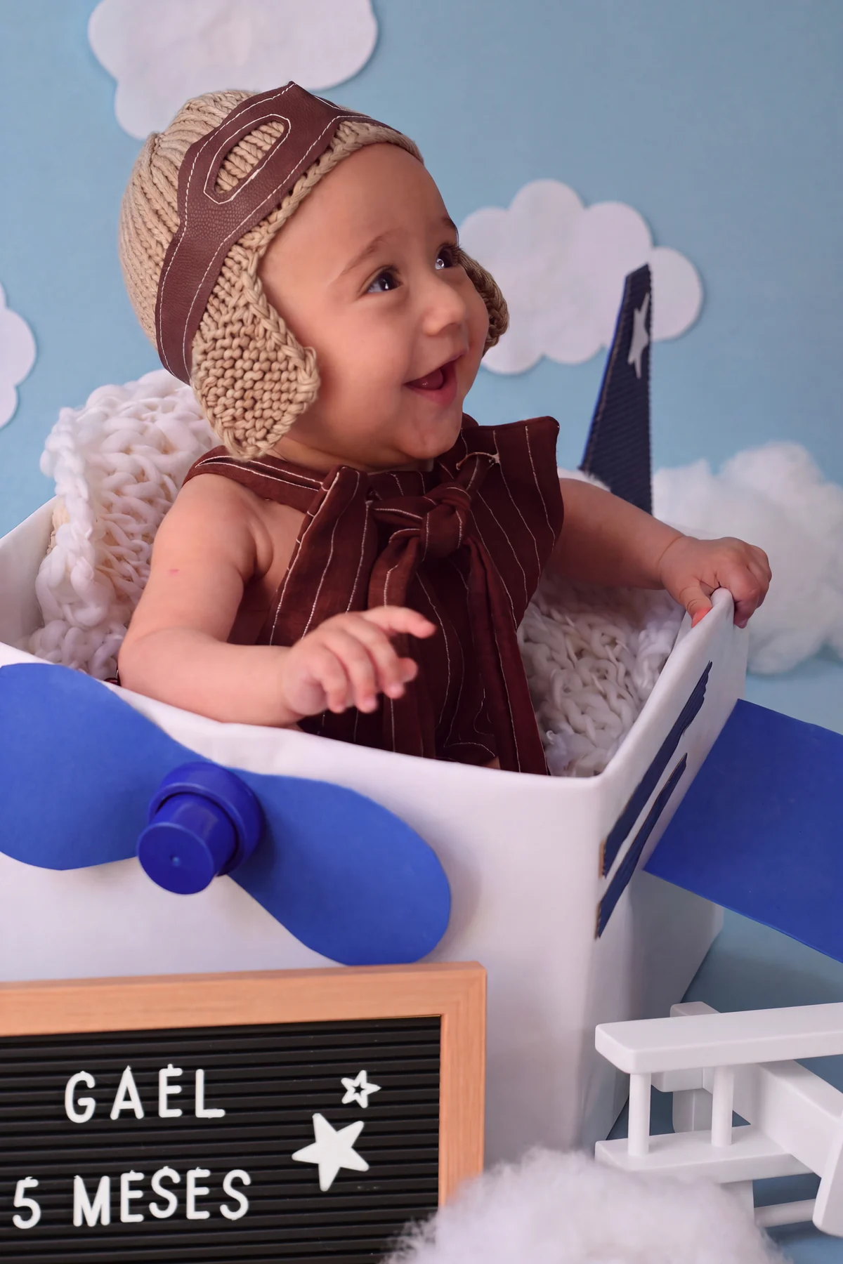 Bebê sorrindo em cenário de avião durante acompanhamento de cinco meses