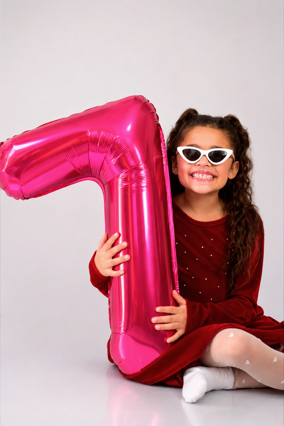 Menina sorrindo com balão de sete anos durante ensaio de aniversário
