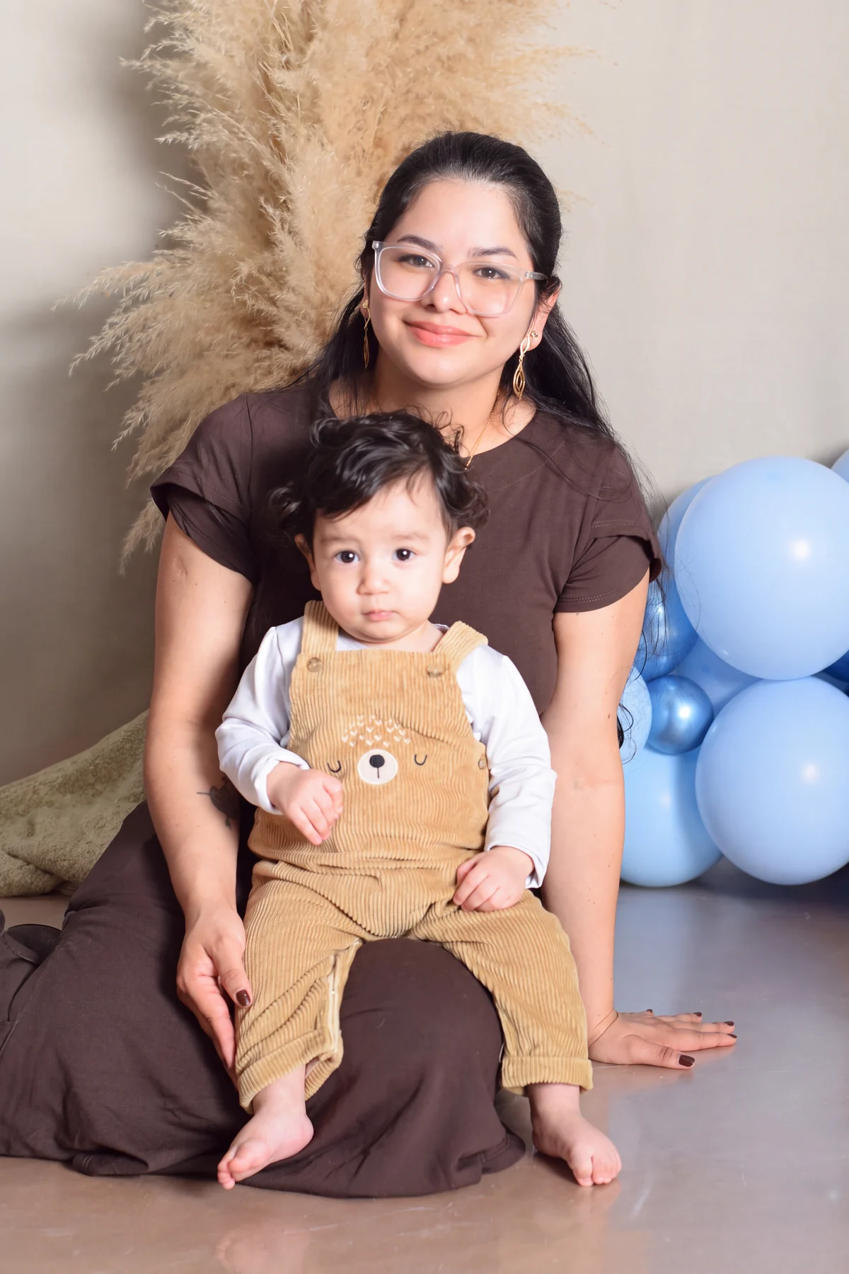 Mãe com seu bebê no colo em cenário de primeiro aniversário