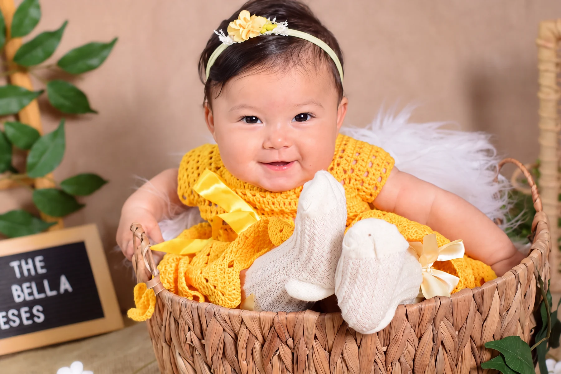 Bebê sorrindo com roupa amarela em cenário de frutas