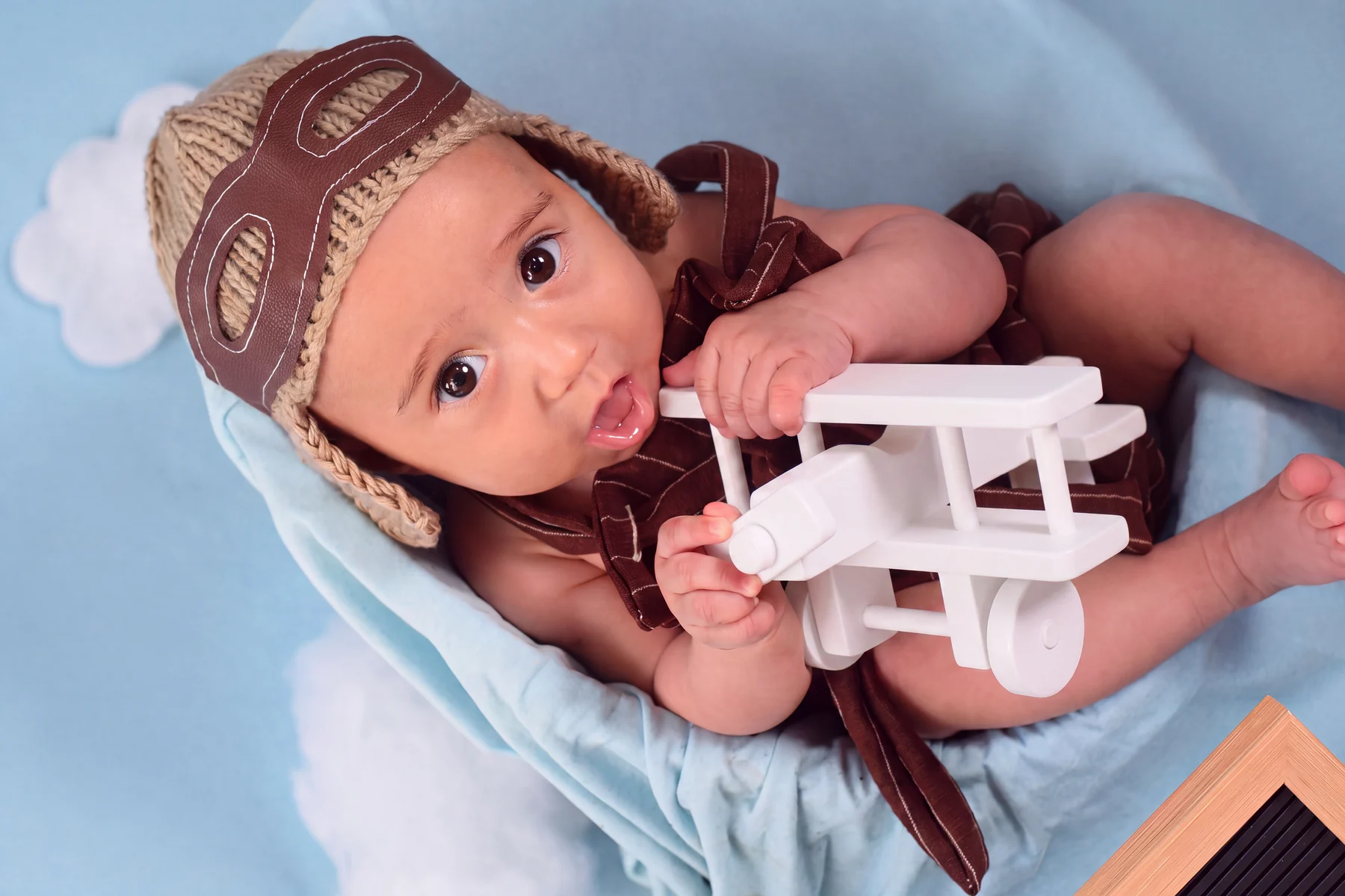 Bebê com touca de aviador e avião de brinquedo em ensaio de acompanhamento